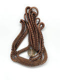 This Pendant features asymmetrical layers of hand wrapped, woven and coiled copper wire with a quartz bead accent.