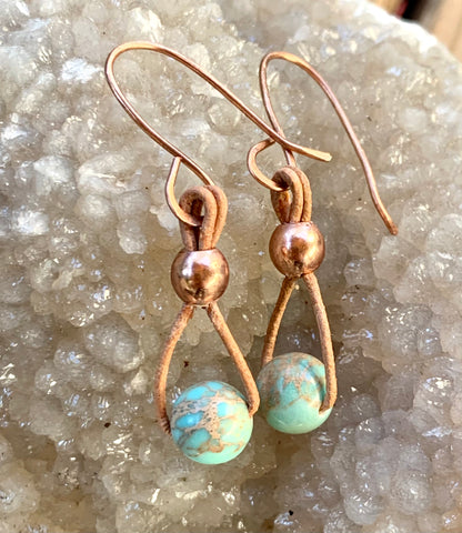 These lightweight earrings feature light turquoise Impression Jasper hanging from tan leather with copper bead accents on handmade copper ear wires.