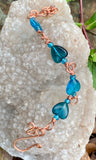 This adjustable copper bracelet has alternating blue glass hearts and a handmade copper clasp.
