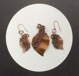 This stunning set features hand-cut, formed, and textured solid copper leaves, expertly wrapped with intricately woven copper. The pendant and matching earrings showcase the beauty of artisanal craftsmanship, capturing the organic elegance of nature. The rich, warm tones of the copper create a harmonious and versatile look, perfect for adding a touch of rustic charm to any outfit. This unique set makes a thoughtful gift for nature lovers or a beautiful addition to your own jewelry collection.