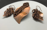 This stunning set features hand-cut, formed, and textured solid copper leaves, expertly wrapped with intricately woven copper. The pendant and matching earrings showcase the beauty of artisanal craftsmanship, capturing the organic elegance of nature. The rich, warm tones of the copper create a harmonious and versatile look, perfect for adding a touch of rustic charm to any outfit. This unique set makes a thoughtful gift for nature lovers or a beautiful addition to your own jewelry collection.