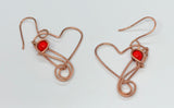 Cute dangling copper heart earrings with a red bead accent.