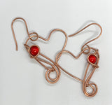 Cute dangling copper heart earrings with a red bead accent.