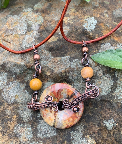 Copper wire wrapped Crazy Lace Agate Donut Necklace with Copper and Lace Agate bead accents on a leather cord.
