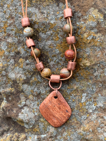 This necklace features a Petrified Wood Focal with Copper tube beads and Picasso Jasper Beads alternating in tan leather with handmade leather clasp