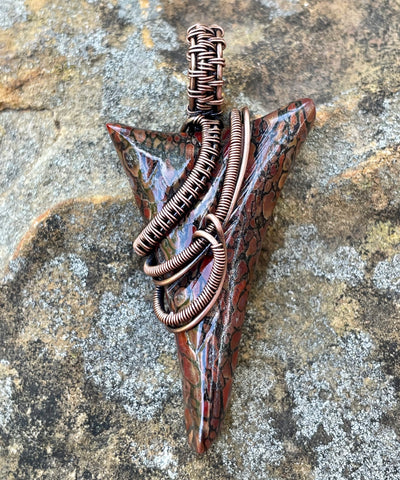 Carved Dinosaur Bone Gemstone Pendant in Wire Wrapped Copper. It has black spider web cell structure filled with various colored agate. 