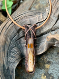 Necklace made of petrified palm wood with a glass bead accent, leather cord, and copper wrapping.