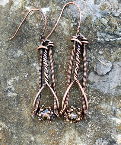 Hand coiled and twisted copper Earrings with sparkling crystals at the bottom.