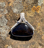 This Velvet Obsidian Pendant is a stunning piece of jewelry featuring an obsidian stone that appears black in some lights but reveals burgundy and purple ripples under certain angles of light. This unique visual effect, combined with its sleek Sterling Silver (.925) setting, makes the pendant both elegant and captivating. The pendant is perfect for those who appreciate jewelry that exudes mystery and sophistication.