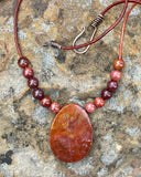 This Necklace Features a Red Jasper Focal with Red Jasper Beads on Leather with a Copper Clasp. 