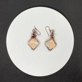 These Delightful Peach and Gray Maligano Jasper Earrings are a unique and striking combination of natural beauty and artisan craftsmanship. Featuring beautiful peach and gray Maligano Jasper stones, these earrings are wrapped in copper wire for an earthy yet elegant look. Paired with hypoallergenic niobium ear wires, these earrings are both stylish and comfortable, perfect for those with sensitive skin.