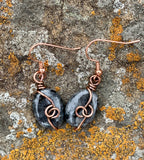 These elegant earrings feature shimmering Larvikite stones wrapped in warm copper, highlighting their natural silvery-blue flashes. The earthy tones of copper beautifully complement the mystical glow of Larvikite, creating a unique and eye-catching pair.