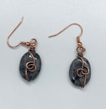 These elegant earrings feature shimmering Larvikite stones wrapped in warm copper, highlighting their natural silvery-blue flashes. The earthy tones of copper beautifully complement the mystical glow of Larvikite, creating a unique and eye-catching pair.