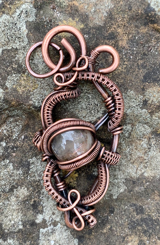 Shimmering Star Sunstone pendant in heavy gauge copper and handwoven and coiled copper weaves.