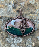 This Ocean Jasper Pendant is a beautifully handcrafted jewelry piece wrapped in Copper, featuring a striking Tree design alongside a delicate Moon accent. The pendant's centerpiece is a naturally vibrant Ocean Jasper stone, showcasing a range of earthy tones that resemble the serene beauty of nature.