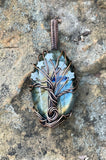 Immerse yourself in the mystical allure of the Labradorite Tree of Life Pendant. This captivating piece features a striking combination of dark, stormy Labradorite and vibrant Amazonite stars, all elegantly wrapped in copper. It’s a perfect representation of the enchanting beauty of a dark, stormy night.